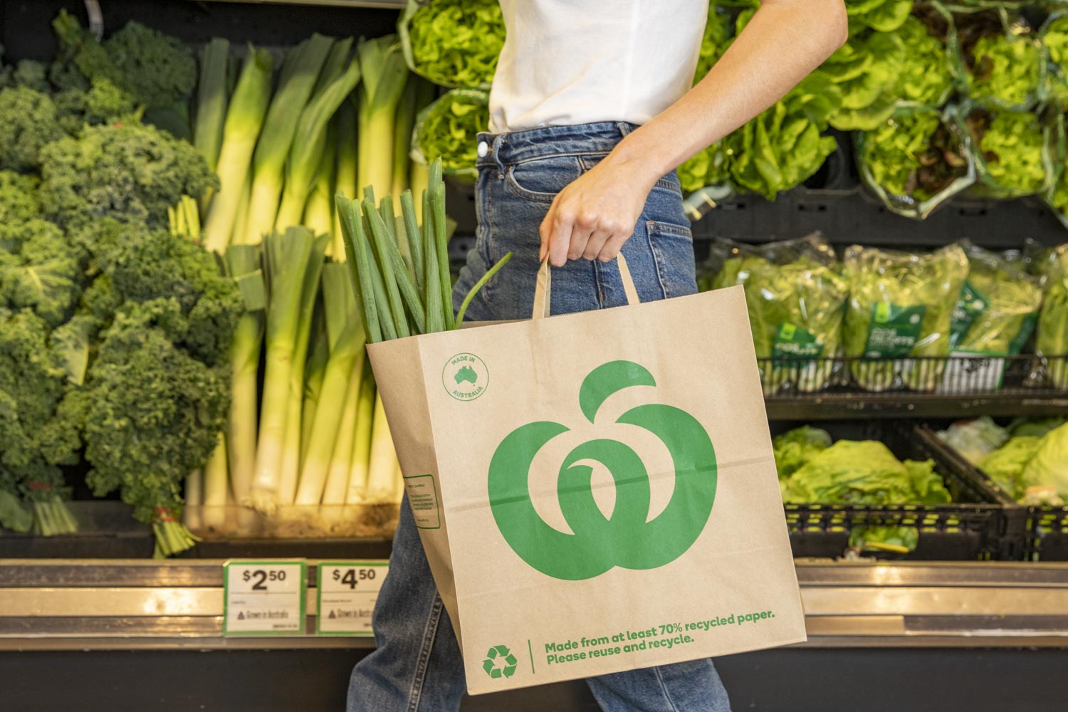 Women holding Woolworths paper carry bag.