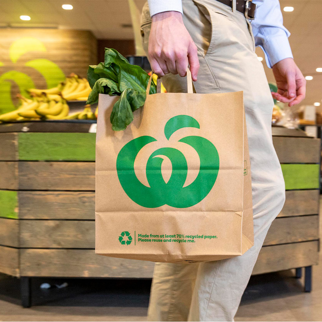 Image of a person carrying a Woolworths paper carry bag by Detpak