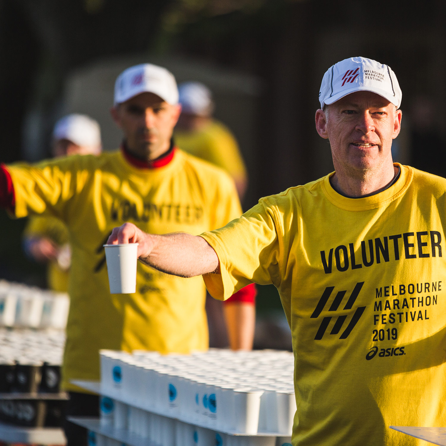 Image of a volunteer at the Melbourne Marathon handing out RecycleMe cups