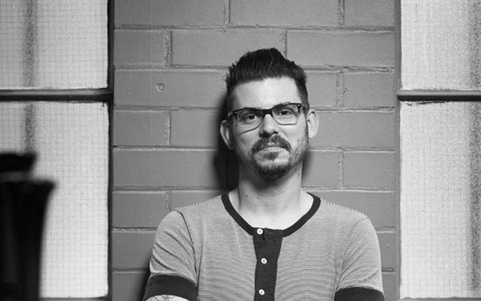 Black and white image of Craig Simon wearing glasses and a black vest