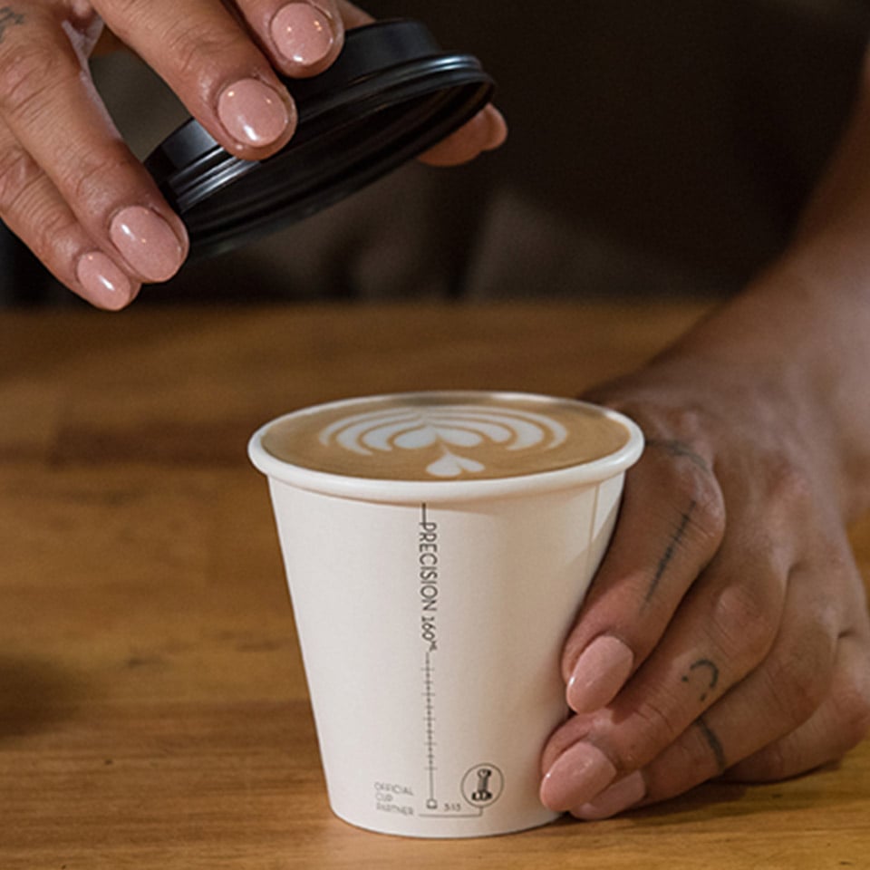 Image of a Detpak Precision Series cup full of coffee and a hand lifting the lid off