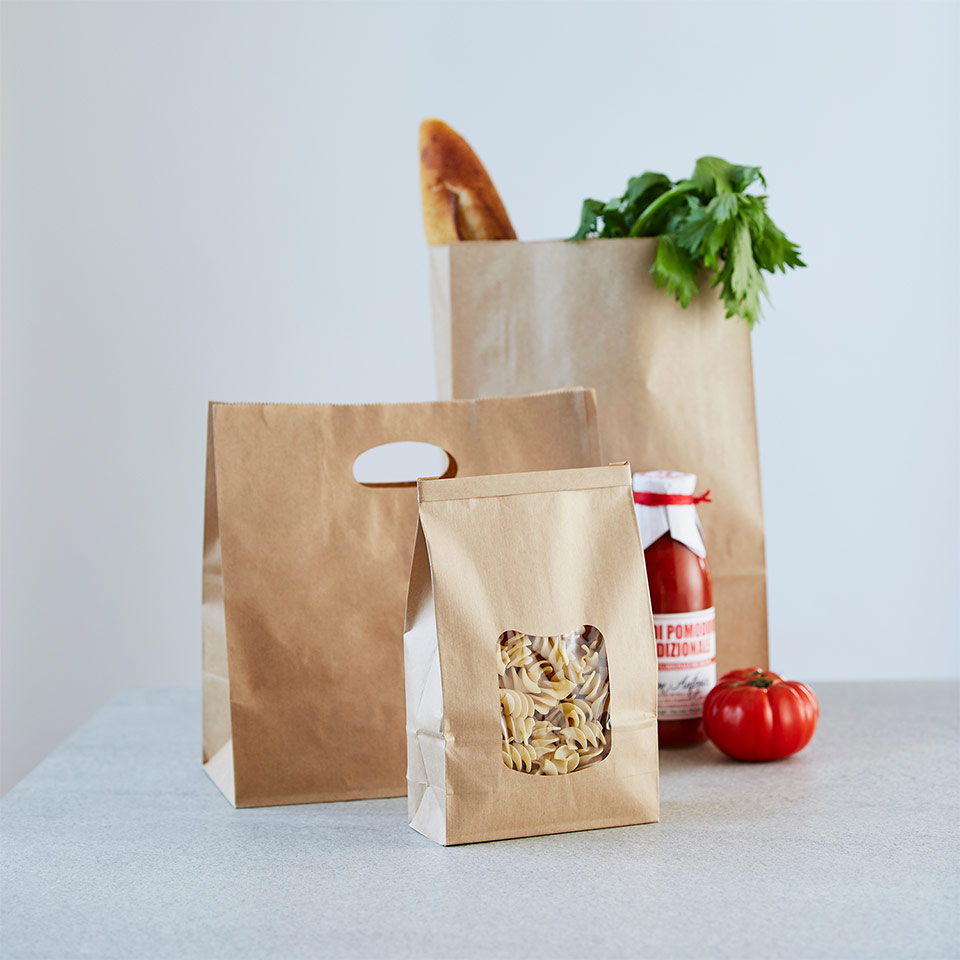 Image of paper bags with tomato and celery and pasta sticking out of the top